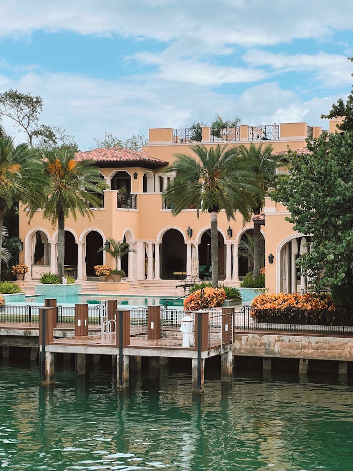Elegant Mediterranean style villa with lush palm trees and waterfront view.