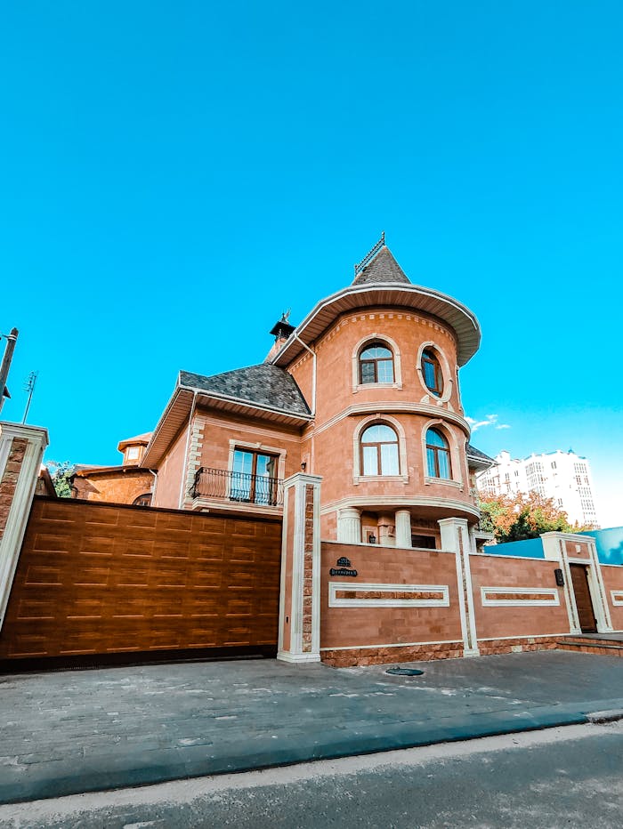 Beautiful brick house with a distinctive tower and clear blue sky backdrop, perfect for real estate listings.